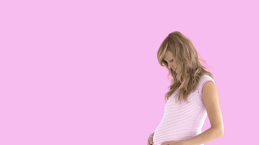 woman expecting a baby holding her belly against a pink screen