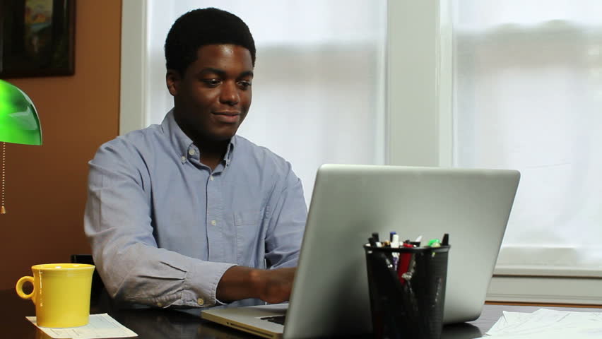 Man typing at computer, laughing