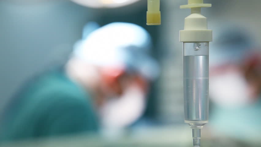 intravenous drip in operation room with surgeons on background