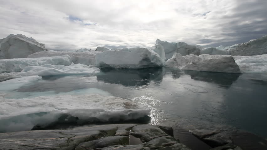 Calm moving water in front of some icebergs. This is the ice-fjord by Ilulissat, Greenland. 