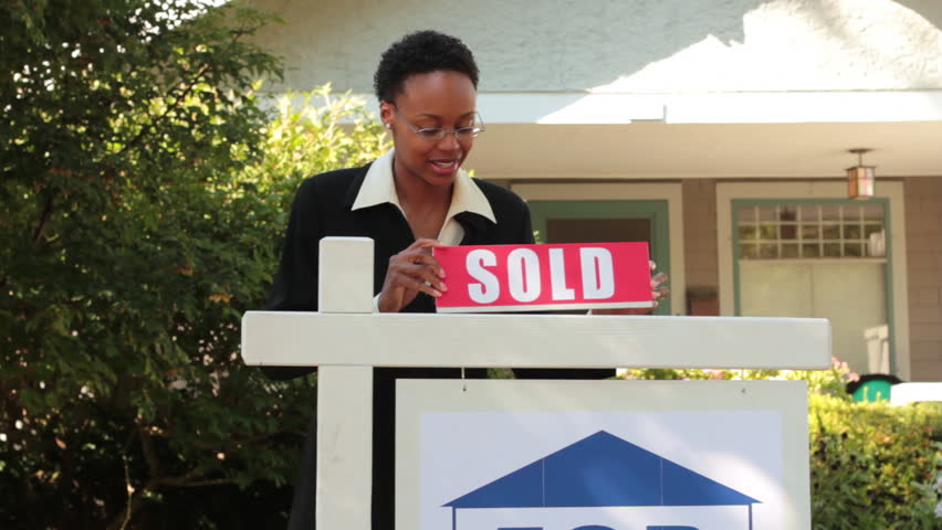 Real estate agent putting up sold sign