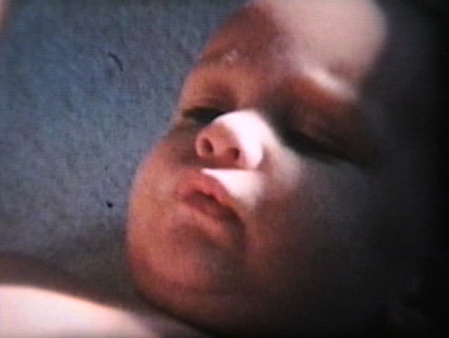 A cute little baby boy nibbles on his toes while his mother changes his diaper.