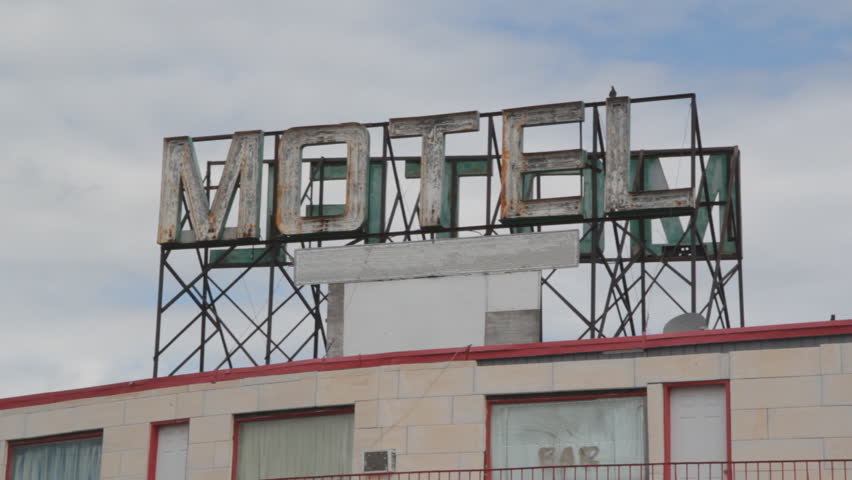 Motel sign. Big sign on top of cheap motel. Pigeons landing.  