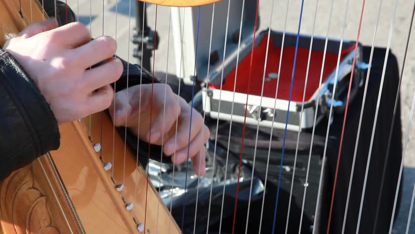 hands of musician play harp outdoors.