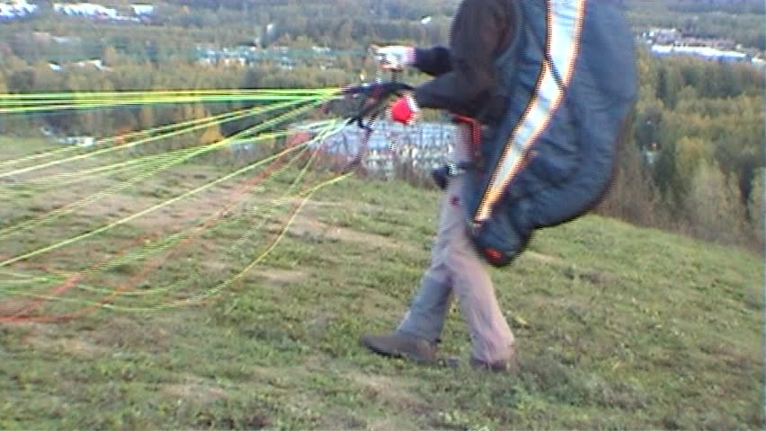 Man checks paraglider ropes before start,  tripod, 16x9