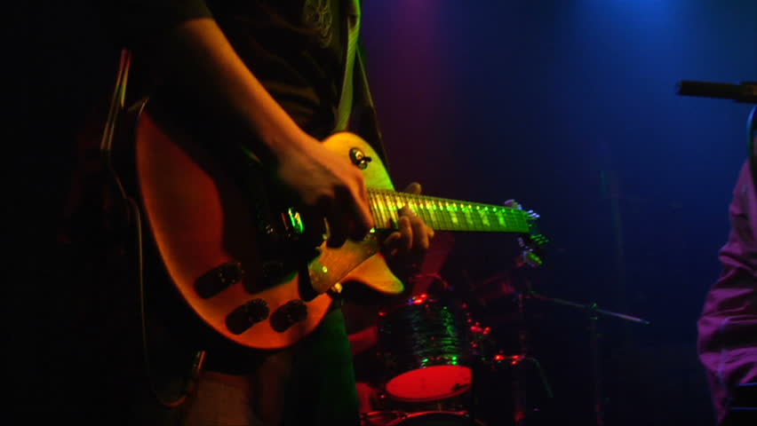 This is a close up shot of a man playing a guitar at a rock concert at a popular club on the Sunset Strip in Los Angeles.