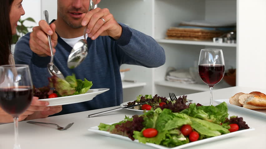 Man serving salad to his wife during lunch in the kitchen