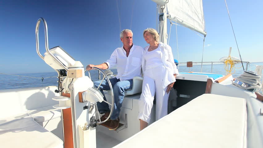Healthy retired couple steering a course aboard their luxury sailing boat