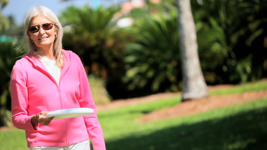 Retired lady keeping fit having fun playing with a sport disc 