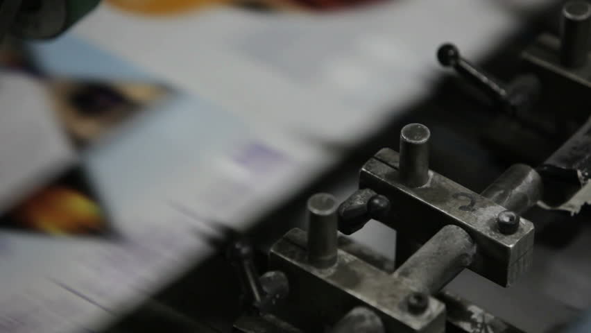 A professional printing press in action, churning out a magazine.