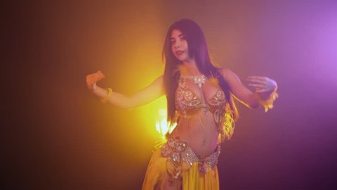 Hot Nude Orient Beach - Alluring sexy traditional oriental belly dancer girl dancing on yellow neon  smoke background. woman in exotic costume with feathers sexually moves her  semi-nude body