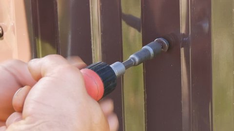 Hand Screwdriver And Screws Cut Into The Iron Sheet Metal Close View Men S Hands Repairing A Fence