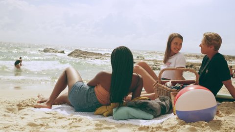 Millennial friends having a picnic on a sandy beach in Australia on a warm summer day.