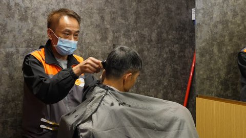Hong Kong March 10 2018 Barber Man Using Electric Trimmer To Finish Hair Cut Of Mature Customer Affordable Haircut Service Room At Hong Kong Marketplace Hairdresser Wear Face Mask