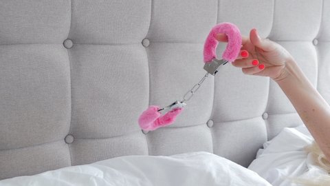Pink Sexy Fluffy Handcuff Hanging On Female Finger Closeup Erotic Sex Game With Sexual Bdsm Toy In Bedroom Interior No Face