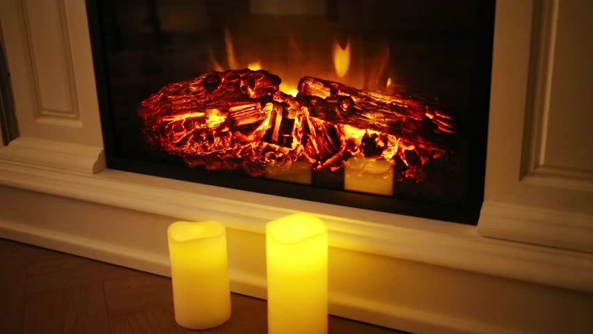 Burning Flame And Logs In Electric Fireplace And Three Candles
