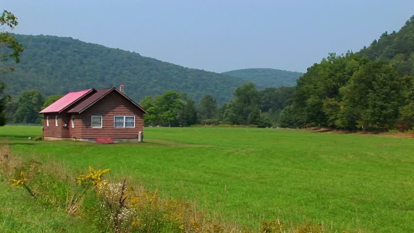 A Cabin In The Middle Of A Green Field Near The Allegheny Mountains