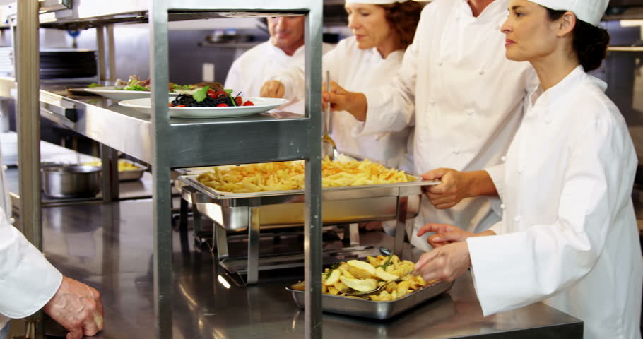Restaurant Kitchen Chefs group of chefs talking cooking and slicing vegetables in a Restaurant Kitchen Chefs group of chefs talking cooking and slicing vegetables in a