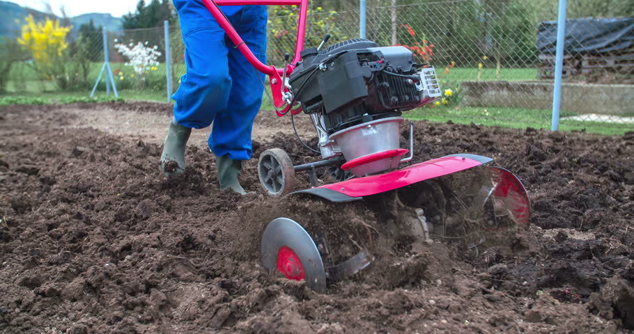 A Senior Man Is Slowly Plowing His Garden With A Cultivator Which ...