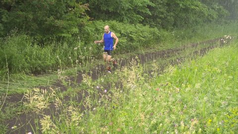 Slow motion. Male runner exercising and training outdoors in nature. traill-running.Rainy day