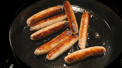 Overhead Closeup frying link sausage in cast iron skillet with audio of sizzling as they cook