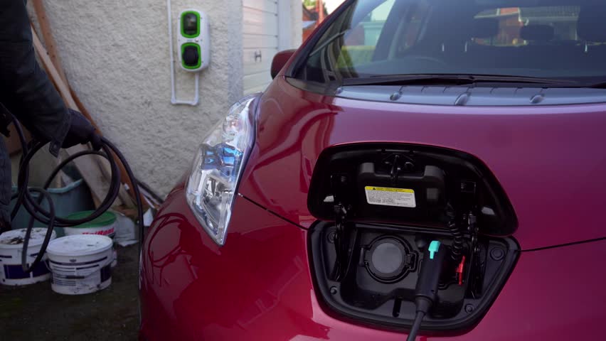 Electric Car Charge Plugged In Stock Footage Video 100 Royalty Electric Car Charge Plugged In By Elderly Caucasian Man Plugs Into And Charger On Wall Station Home Clean Environment Environmentally Friendly