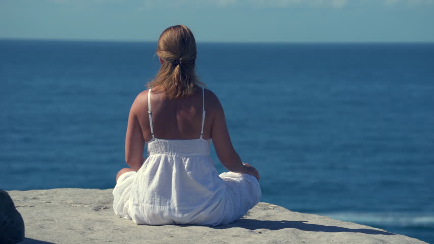 Beautiful Woman in white dress sitting on a rock by the ocean image ...