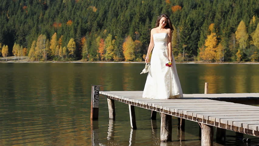 Thoughtful Single Bride Sitting On A Wooden Dock Of A Mountain Lake In ...