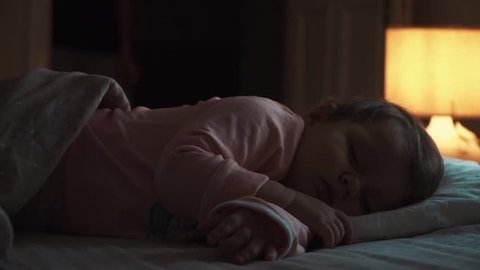 Mother enters the room. sleeping baby happy and carefree, the mother caresses kiss goodnight.