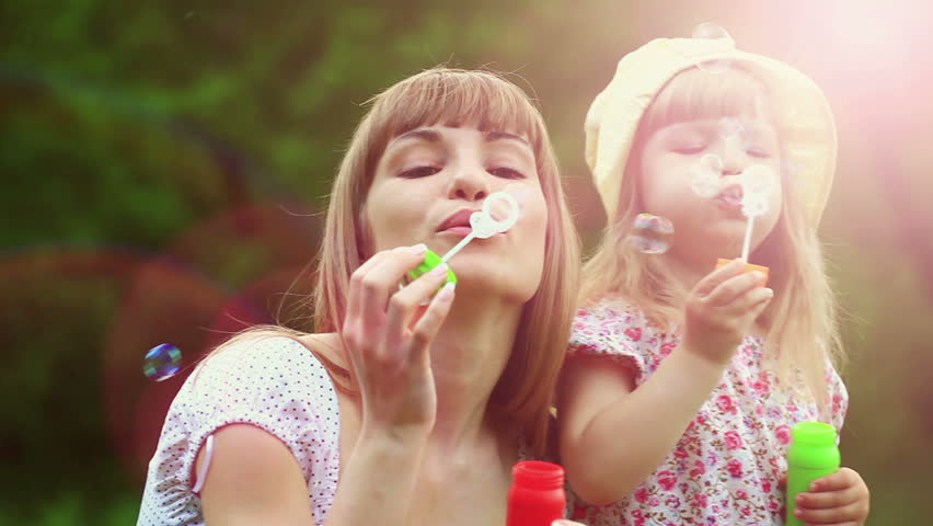 Sunny family blowing air bubbles. Lens flares