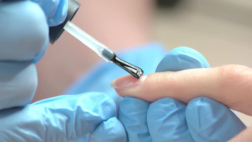 Nail Technician Lying Colorless Varnish Beautician In Cosmetician Lying Polish To Woman Nails In Blue Rubber Gloves Making Manicure