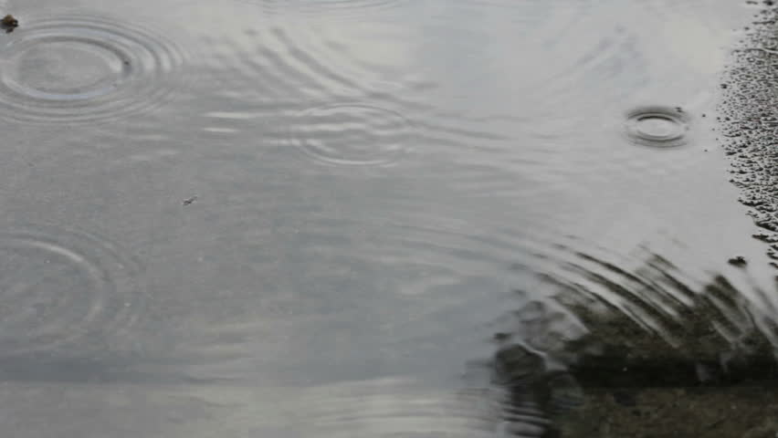 SLOW MOTION CLOSE UP: Raindrops Falling Into Puddle Creating Big ...